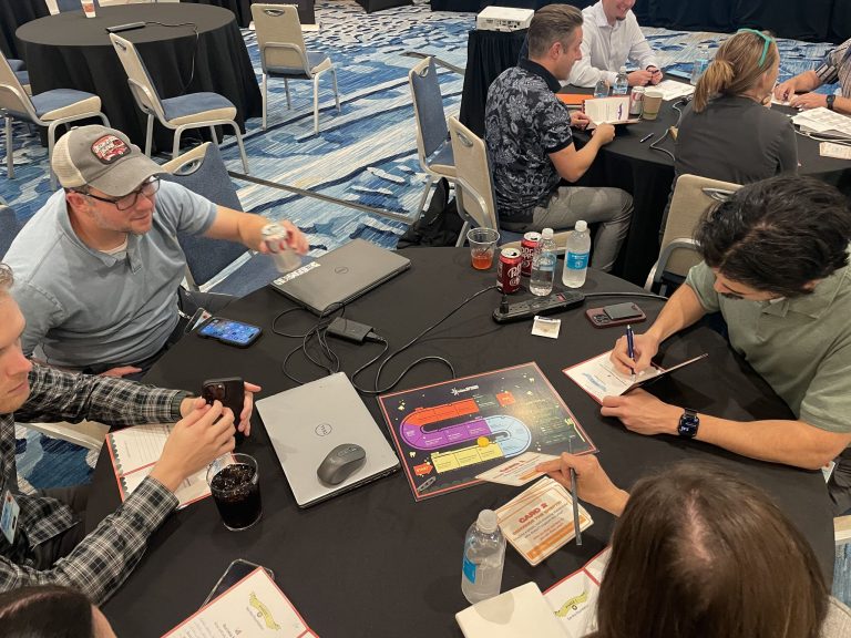 Attendees collaborating around a table during a game at the DSO Tech Summit 2025